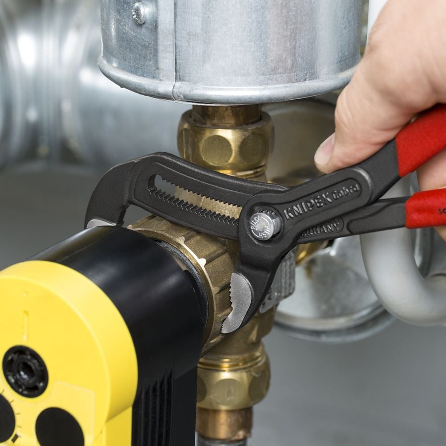 Knipex 9K 00 80 180 US Plumbing 6-Piece Set Cobra water pump pliers gripping a brass plumbing fitting on installed piping during service work